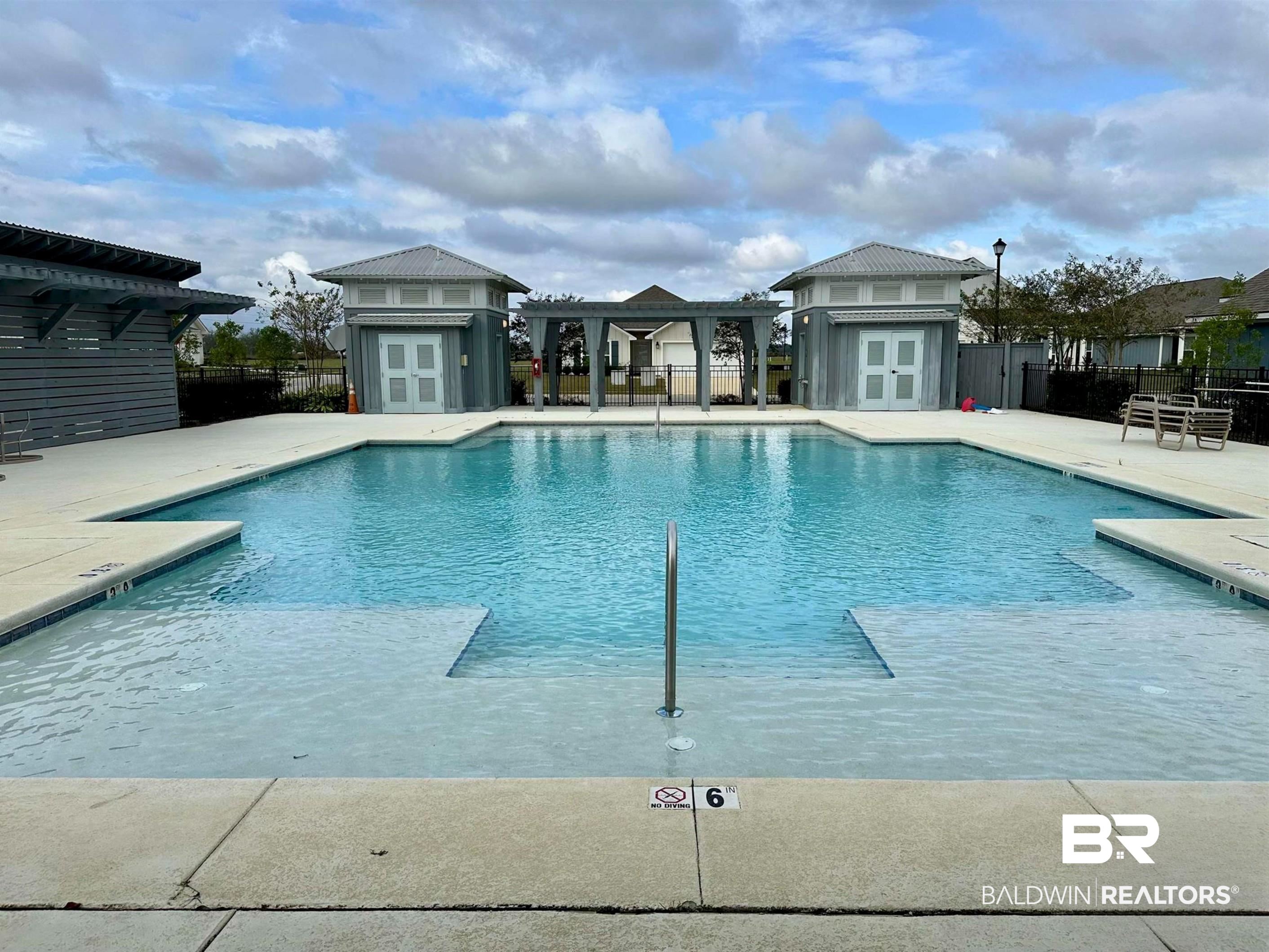 1040 Hayward Loop Foley, AL 36535 - Photo 30 of 35 Resort-style pool with integrated tanning ledges, a stainless steel handrail, and surrounding concrete decking