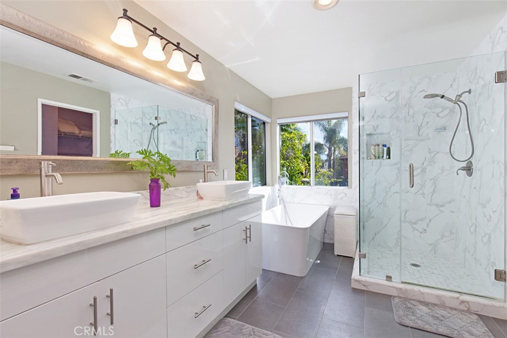 19 Tennessee Irvine, CA 92606 - Photo 28 of 40 a bathroom with a double vanity sink a large mirror a bathtub and next to a window