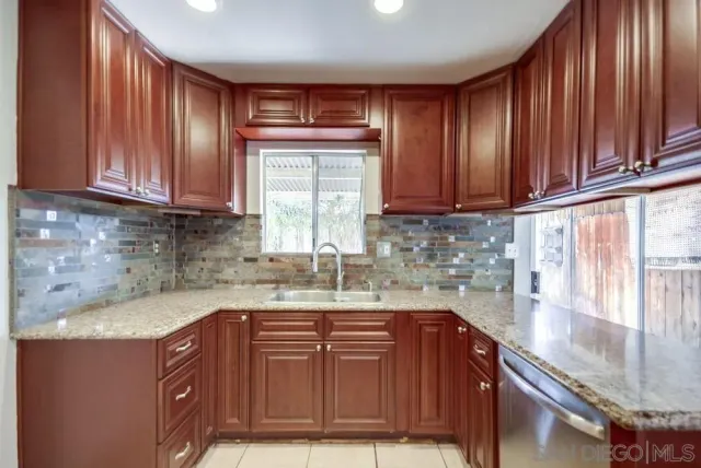 a kitchen with granite countertop wooden cabinets a sink and dishwasher