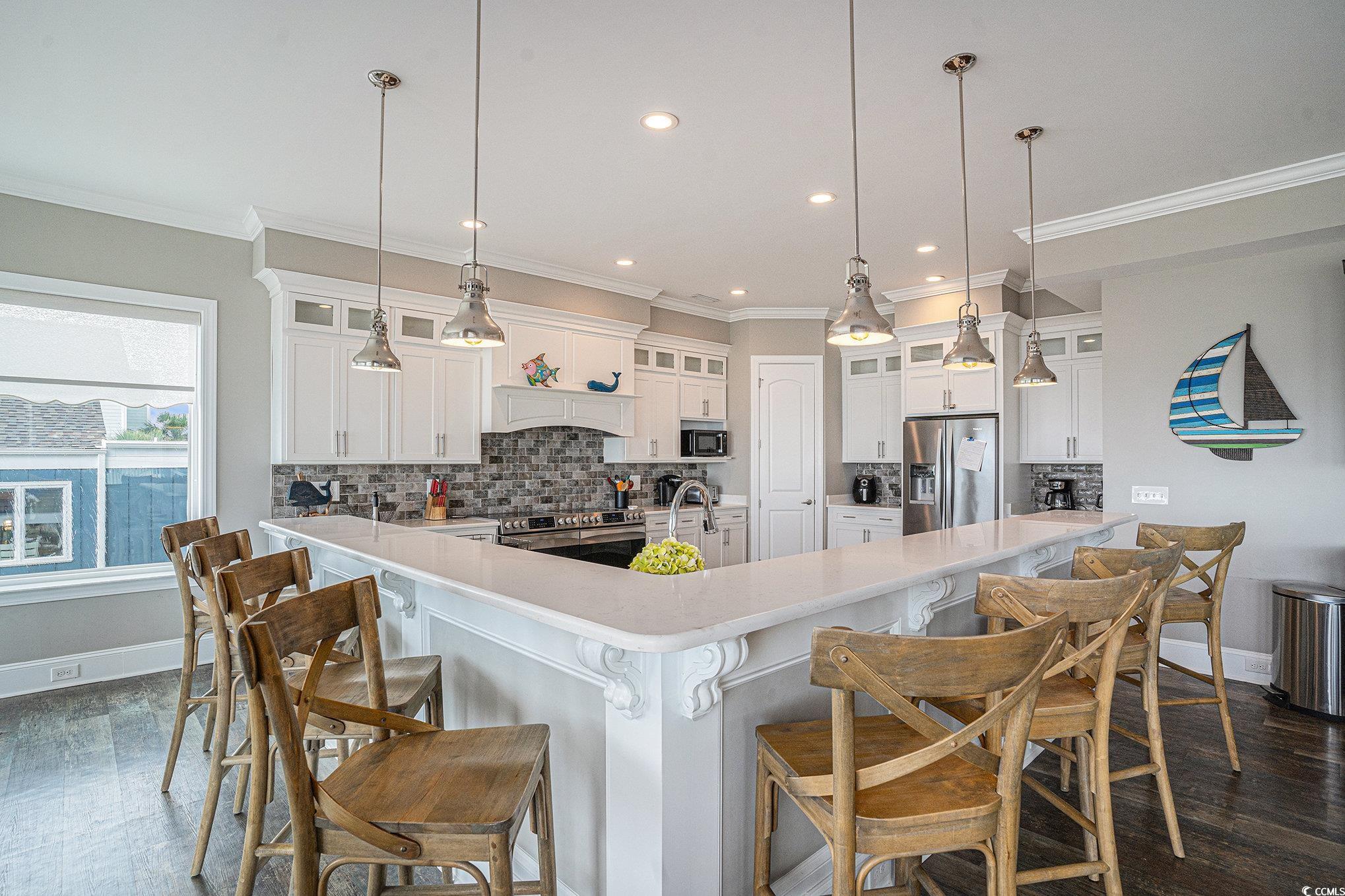 1907 South Waccamaw Drive Murrells Inlet, SC 29576 - Photo 11 of 40 Kitchen featuring stainless steel appliances, white cabinets, decorative light fixtures, decorative backsplash, and a kitchen breakfast bar