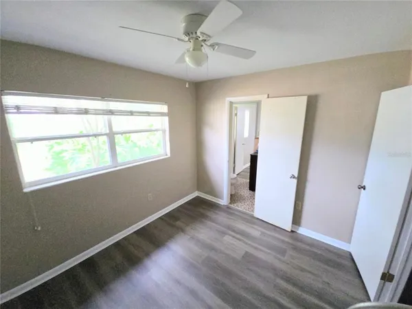 a view of an empty room with wooden floor and a window
