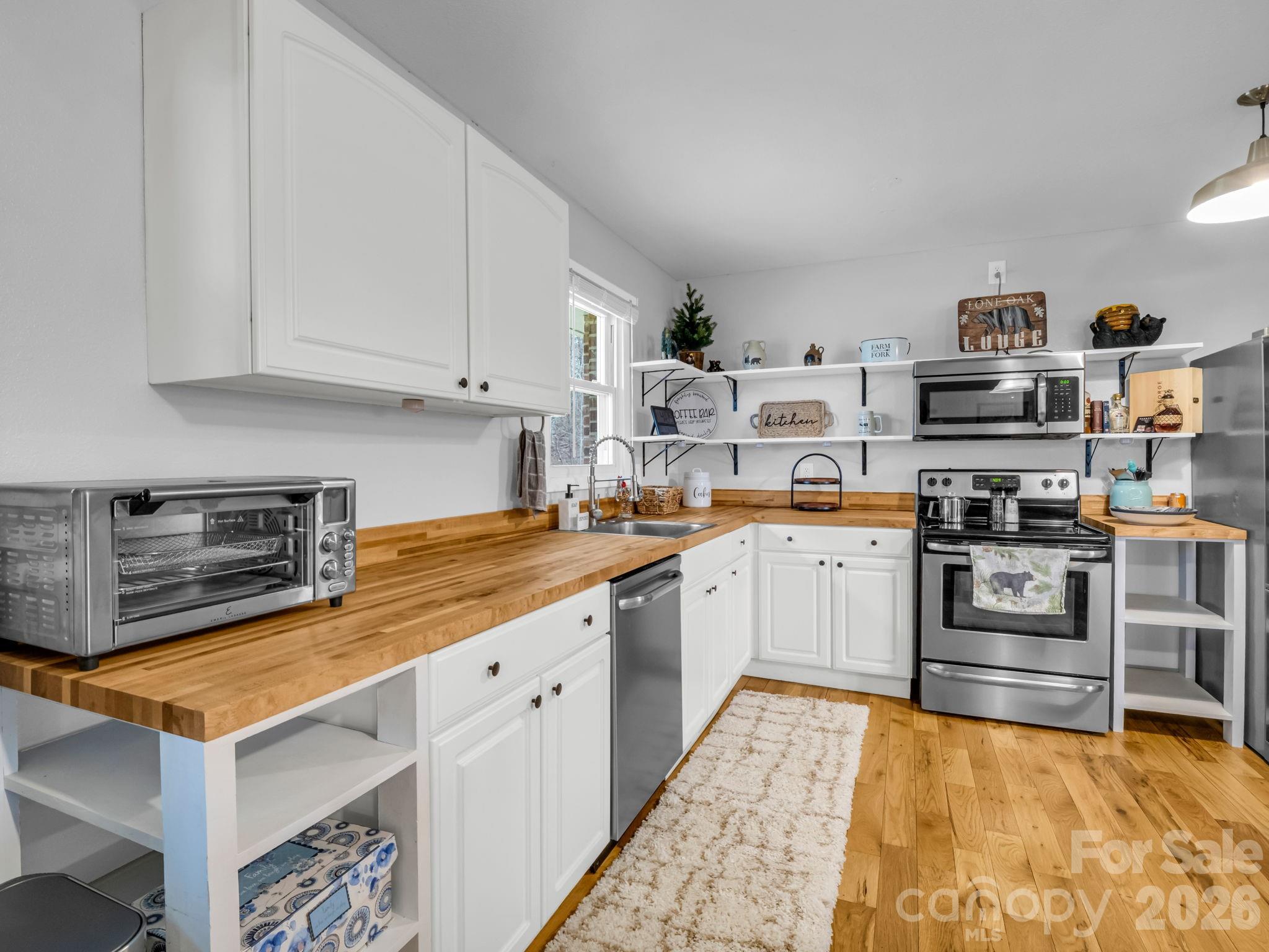 248 Bible School Road Lake Lure, NC 28746 - Photo 19 of 38 a kitchen with stainless steel appliances granite countertop a stove top oven a sink dishwasher and white cabinets with wooden floor