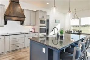 a kitchen with granite countertop a sink a stove and cabinets