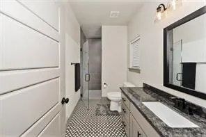 a bathroom with a granite countertop sink a mirror and a toilet