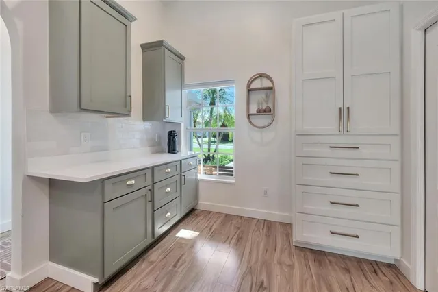 a kitchen with white cabinets and wooden floors