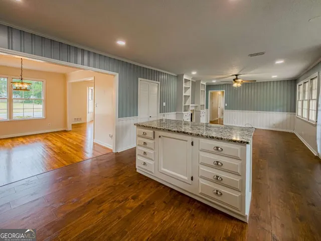 a view of a room with wooden floor kitchen and chandelier
