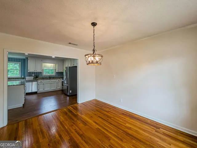 a view of an empty room with chandelier fan and wooden floor