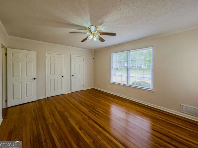 a view of empty room with wooden floor and fan
