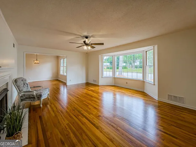 a view of an empty room with a window and wooden floor