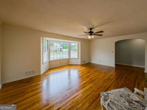 a kitchen with stainless steel appliances granite countertop a refrigerator a sink dishwasher a stove and white cabinets with wooden floor