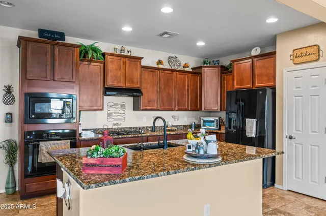 a kitchen with stainless steel appliances granite countertop a sink refrigerator and cabinets
