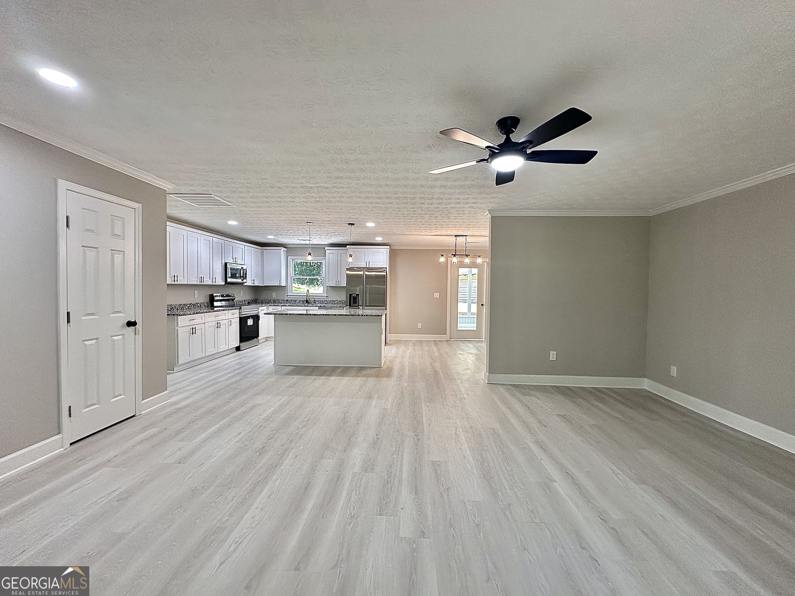 115 Creekside Lane Covington, GA 30016 - Photo 28 of 59 a view of a kitchen with wooden floor a ceiling fan and stainless steel appliances