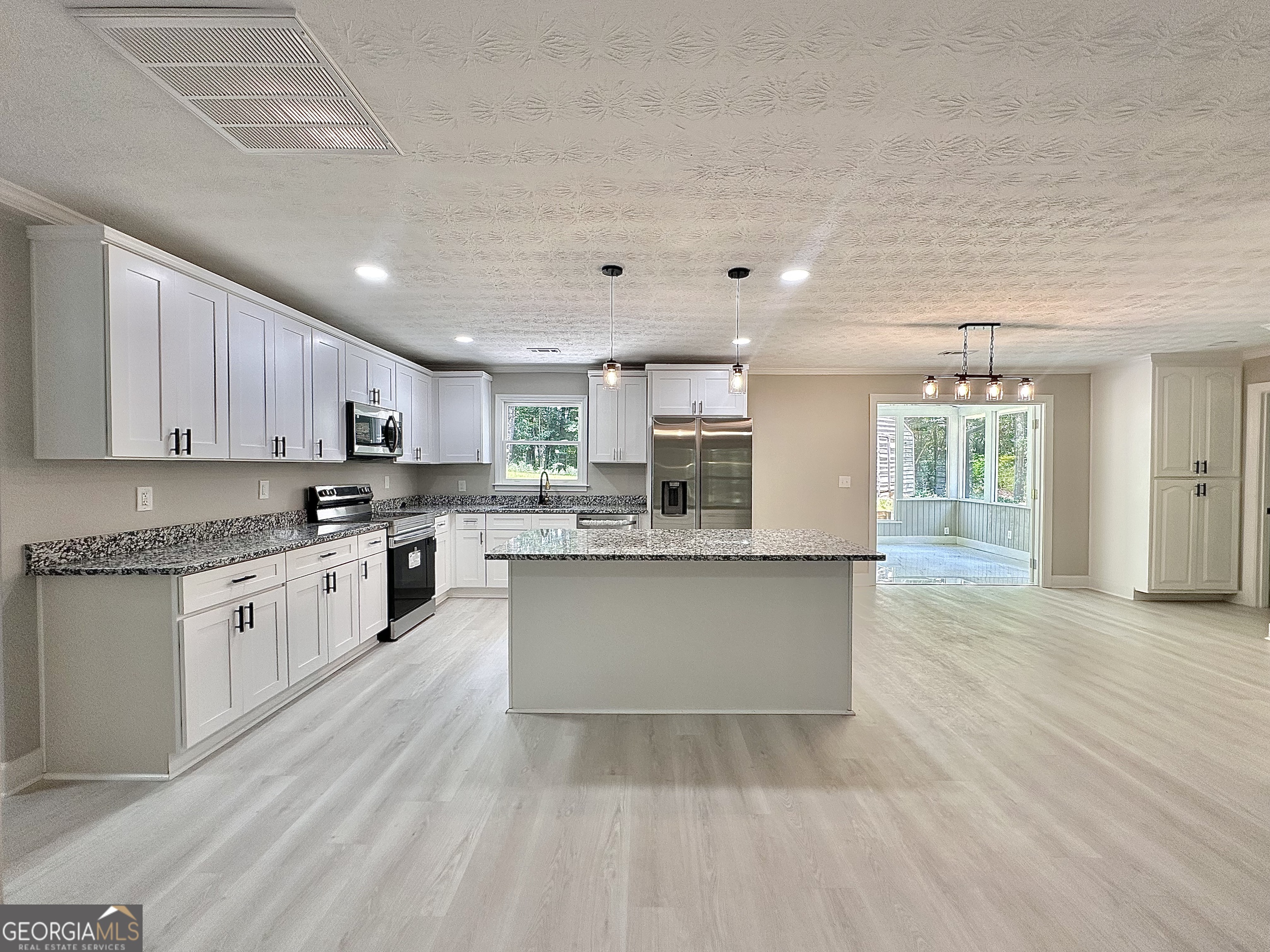 115 Creekside Lane Covington, GA 30016 - Photo 33 of 59 a large kitchen with cabinets wooden floor and stainless steel appliances