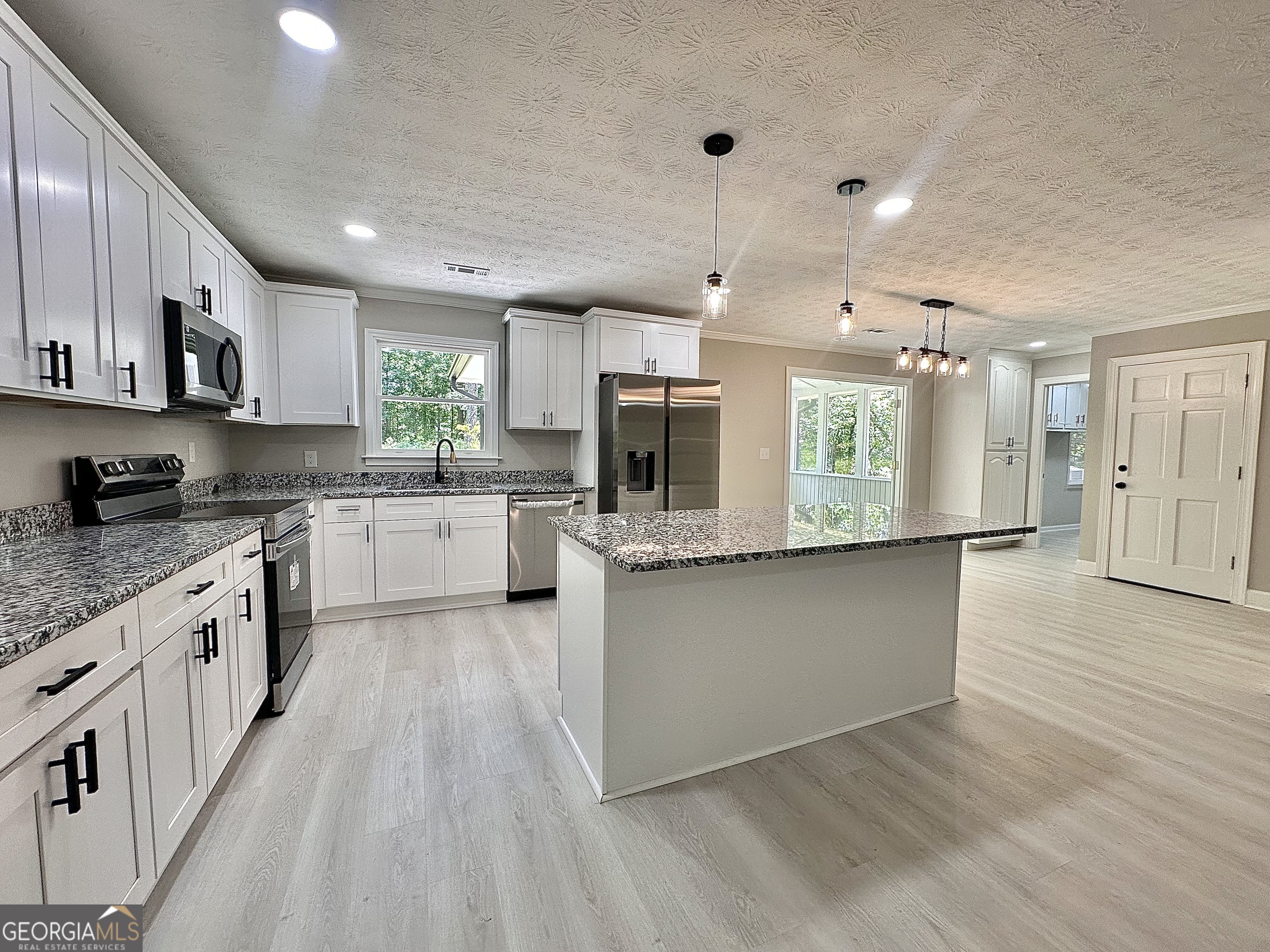 115 Creekside Lane Covington, GA 30016 - Photo 38 of 59 a large kitchen with stainless steel appliances kitchen island granite countertop a stove a sink a refrigerator and white cabinets with wooden floor