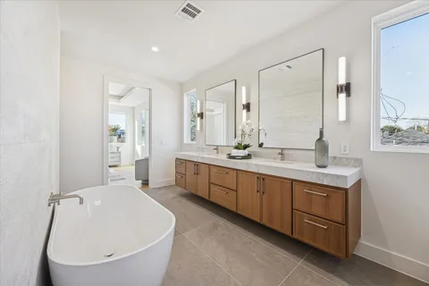 a spacious bathroom with a double vanity sink mirror and bathtub