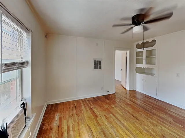 a view of empty room with wooden floor and fan