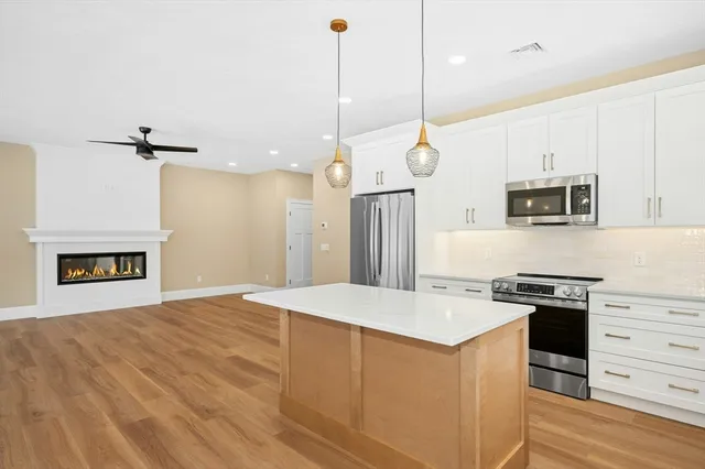 a kitchen with kitchen island a stove a sink and a wooden floor