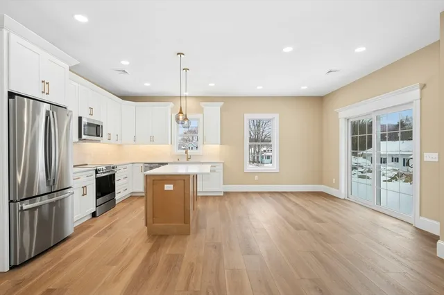 a kitchen with stainless steel appliances granite countertop a refrigerator a sink dishwasher a stove and a wooden floor