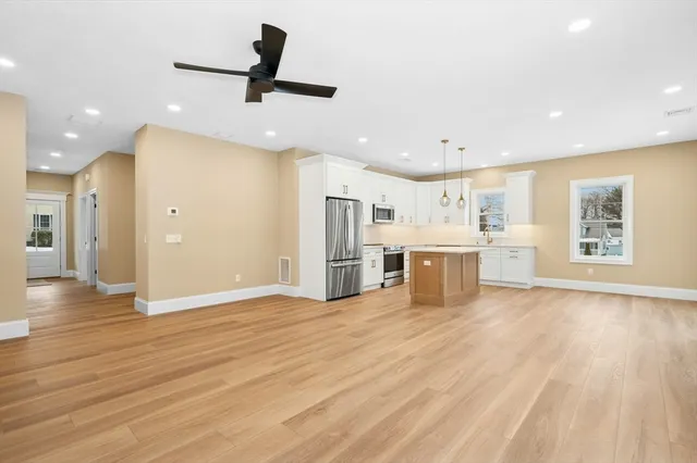 a view of a kitchen with stainless steel appliances a refrigerator stove top oven and cabinets