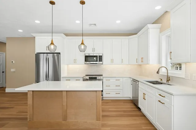 a kitchen with stainless steel appliances granite countertop a sink a stove and a refrigerator