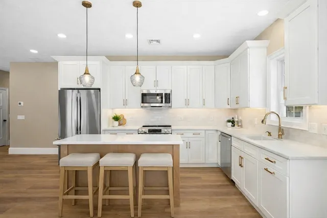 a kitchen with stainless steel appliances granite countertop a sink a stove a refrigerator and island with wooden floor