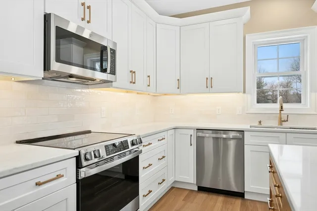 a kitchen with cabinets stainless steel appliances and wooden floor