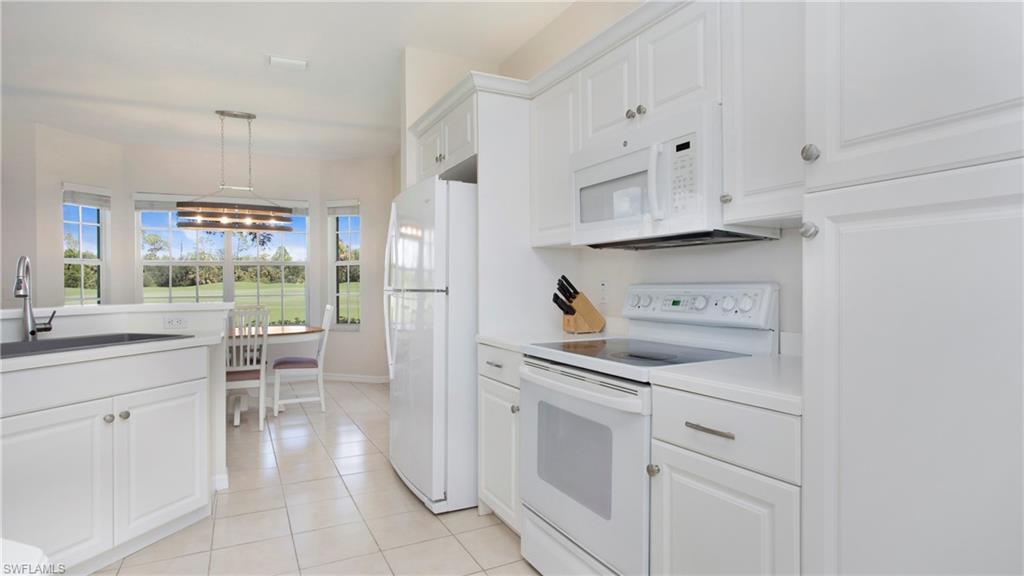 6025 Pinnacle Lane, Unit 6602 Naples, FL 34110 - Photo 4 of 43 a kitchen with white cabinets and appliances