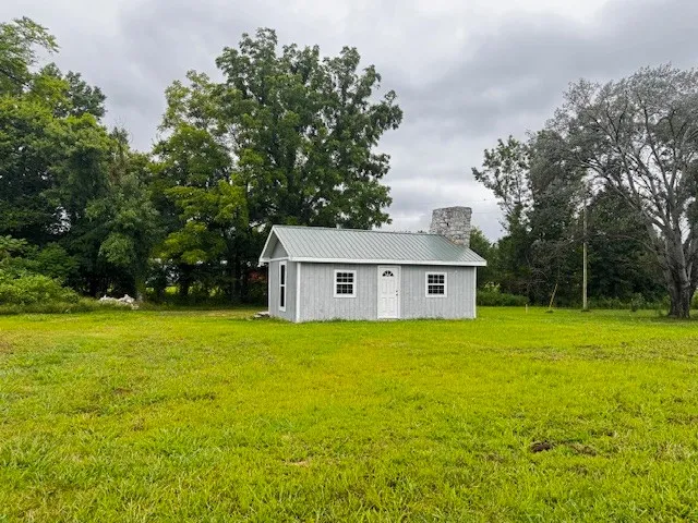 a view of a big yard next to a house with large trees