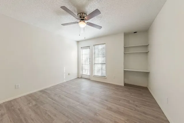 an empty room with wooden floor closet and windows