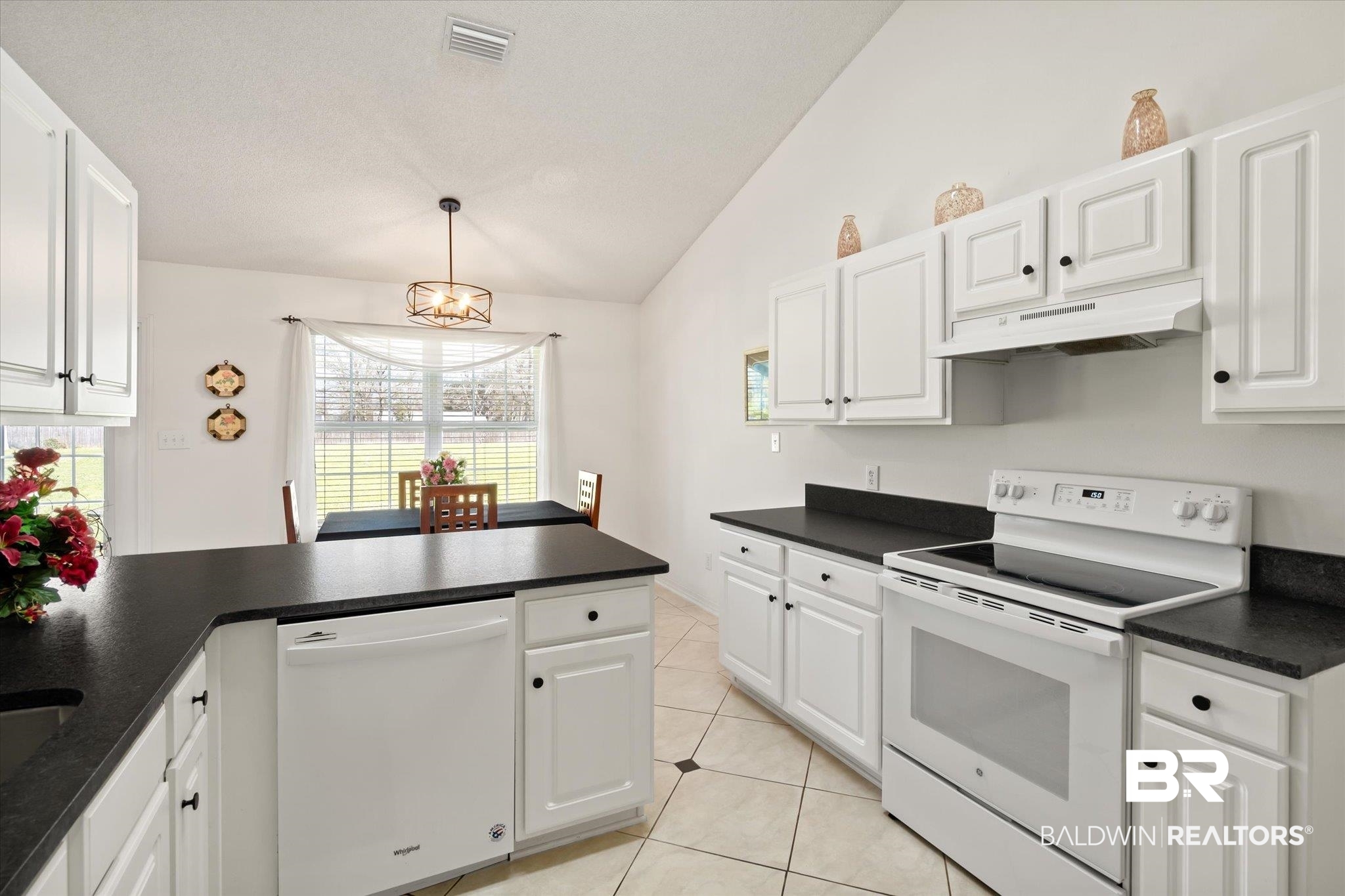 12520 Hunters Chase Foley, AL 36535 - Photo 21 of 32 Kitchen featuring visible vents, under cabinet range hood, white appliances, white cabinets, and lofted ceiling