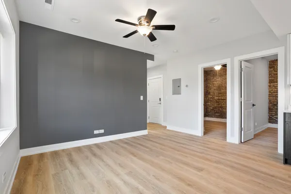 an empty room with wooden floor and a ceiling fan