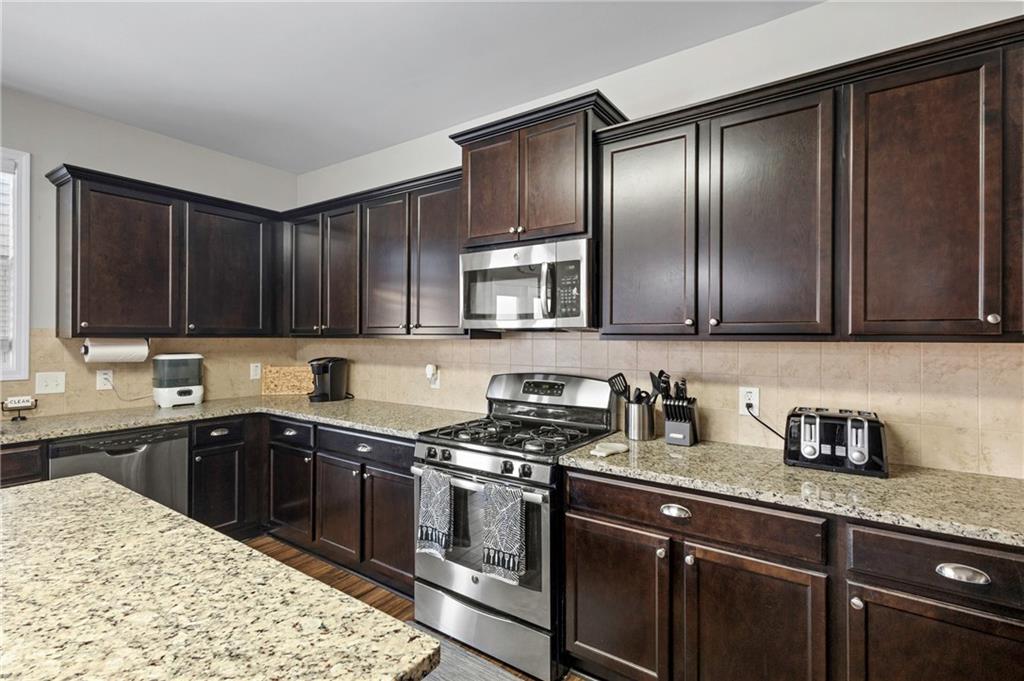 285 Paces Drive Lithia Springs, GA 30122 - Photo 7 of 45 a kitchen with stainless steel appliances granite countertop a sink stove microwave and cabinets
