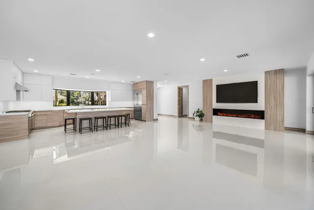 a dining hall with stainless steel appliances granite countertop a stove a sink a refrigerator and white cabinets