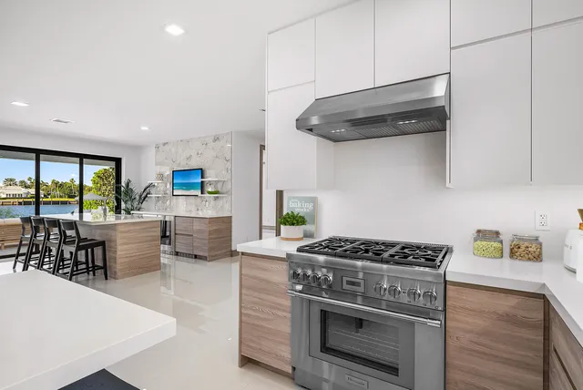 a large white kitchen with large windows and table