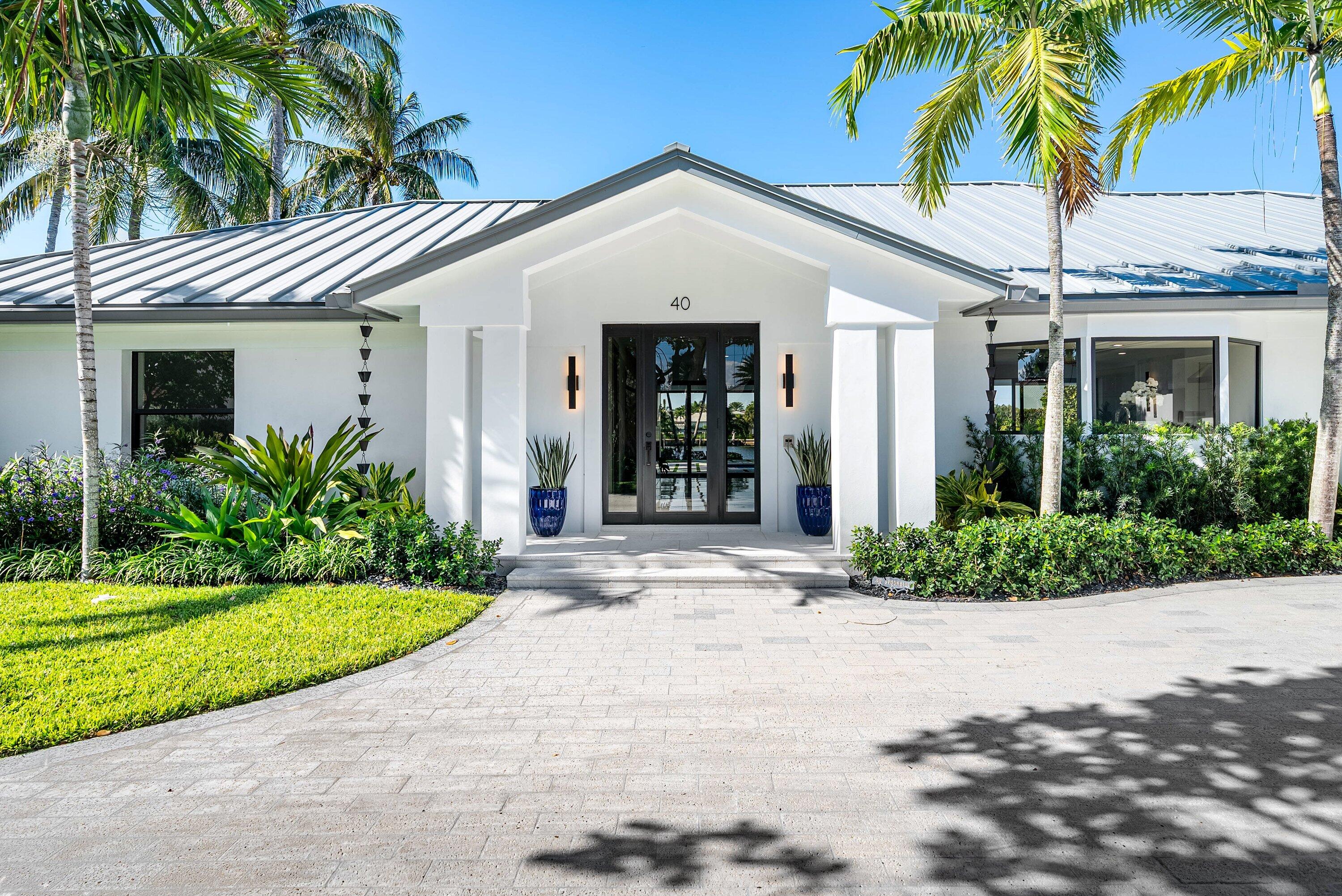 40 Spoonbill Road Manalapan, FL 33462 - Photo 10 of 67 a view of a white house with a large windows and a yard with palm trees