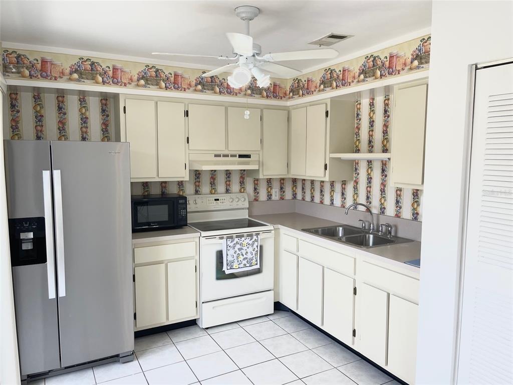 13100 South McCall Road, Unit 125 Port Charlotte, FL 33981 - Photo 6 of 19 a kitchen with stainless steel appliances a white cabinets and a chandelier