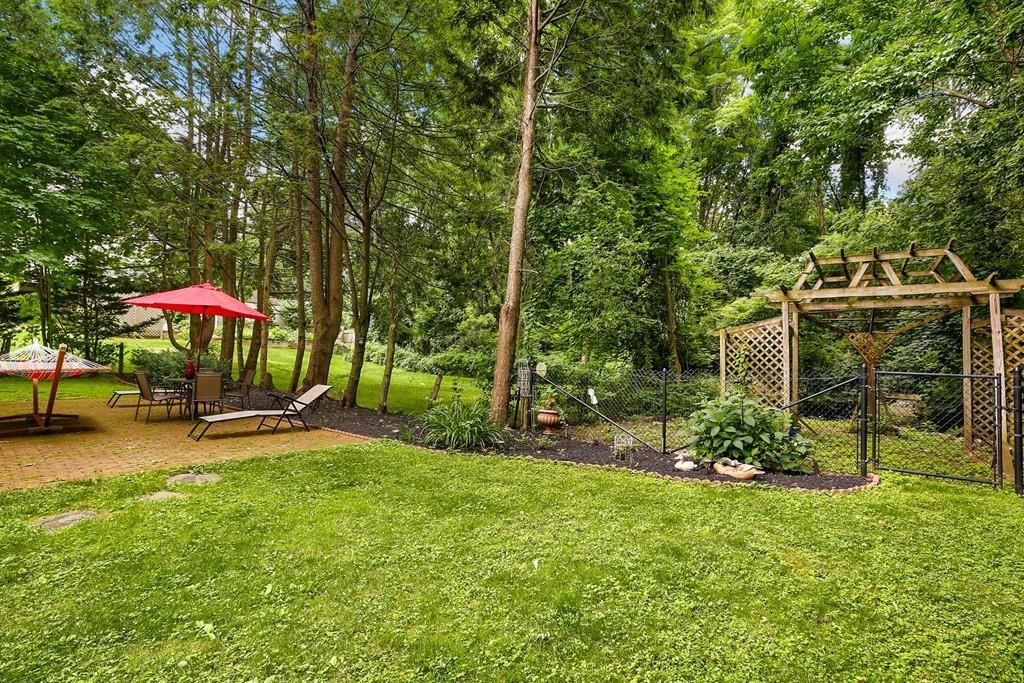 7 Cedar Brook Road Wellesley, MA 02482 - Photo 34 of 36 a backyard of a house with table and chairs under an umbrella