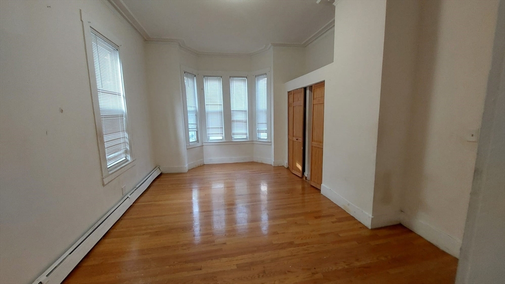 124 Marcella Street, Unit 1 Boston, MA 02119 - Photo 6 of 13 a view of an empty room with wooden floor and a window