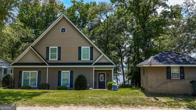 a view of a yard in front of a house with plants and large tree