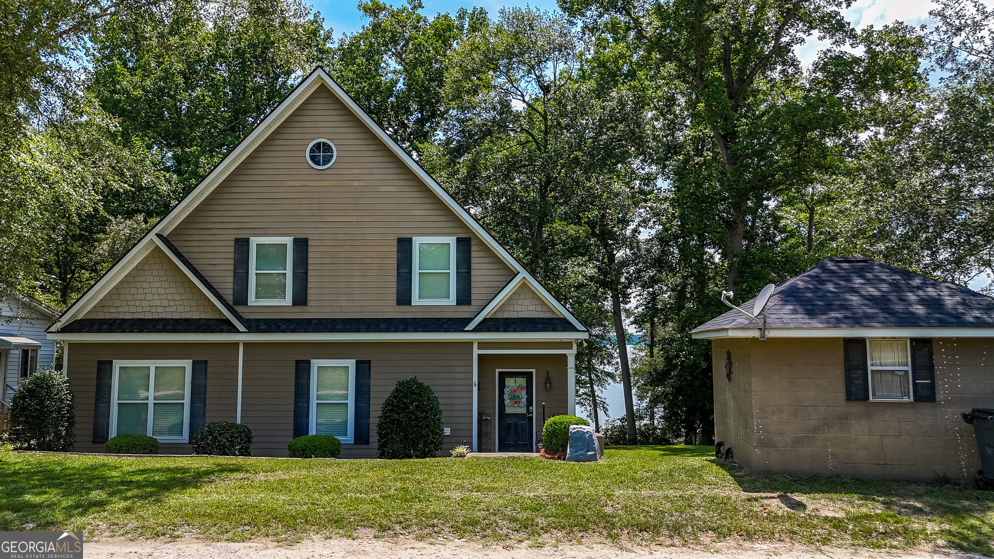 a view of a yard in front of a house with plants and large tree