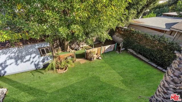 a view of a backyard with table and chairs and a large tree