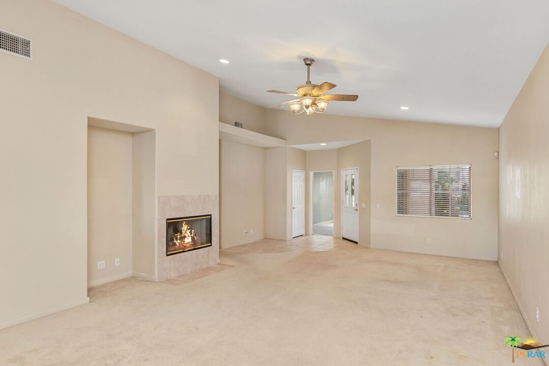 80372 Pebble Beach Drive Indio, CA 92201 - Photo 5 of 35 an empty room with a fireplace and chandelier fan