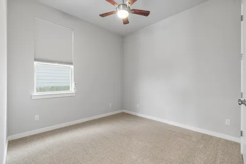 an empty room with window and ceiling fan