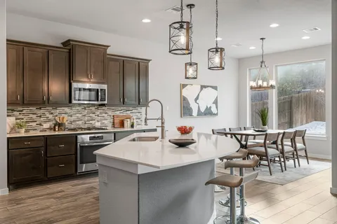 a kitchen with stainless steel appliances a sink a stove a refrigerator cabinets and dining table