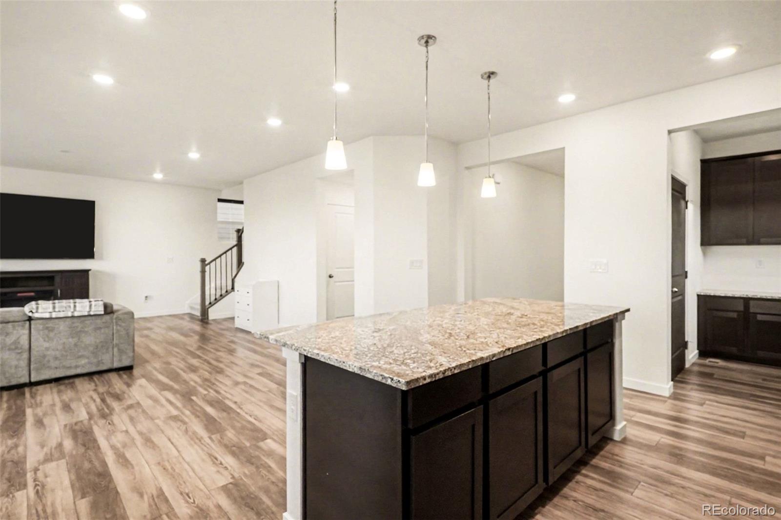 1053 Highpoint Trail Elizabeth, CO 80107 - Photo 8 of 28 a living room with kitchen island furniture and a flat screen tv
