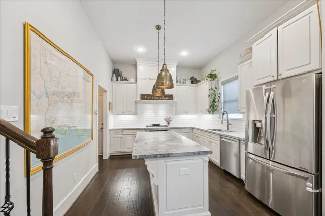 a kitchen with kitchen island a counter top space a sink a refrigerator a stove and a window