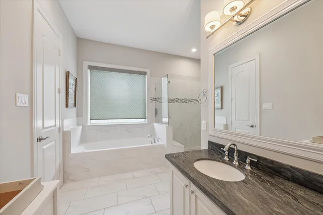 a bathroom with a granite countertop sink a mirror and a bathtub