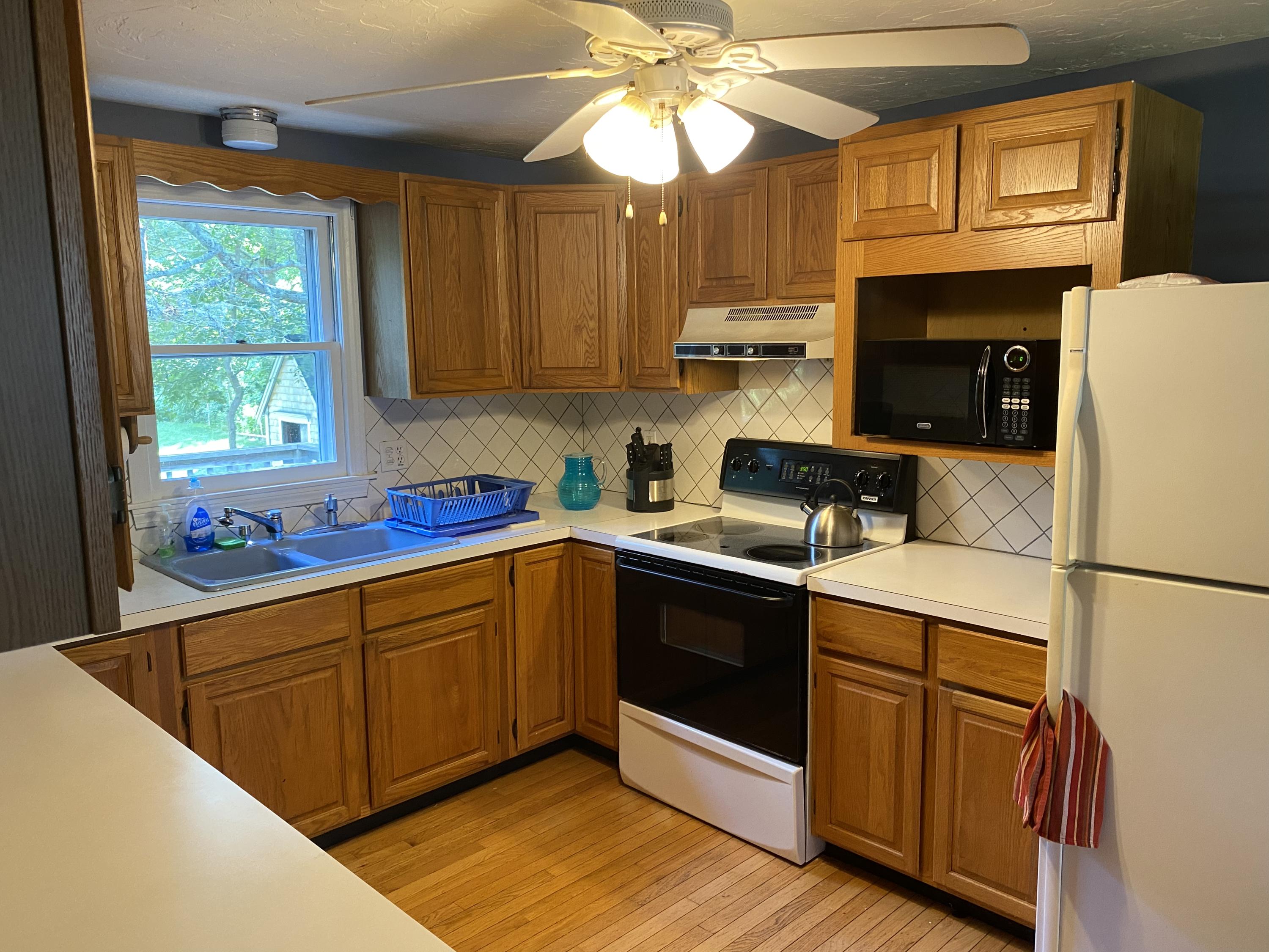 331 Ames Way Centerville, MA 02632 - Photo 3 of 16 a kitchen with stainless steel appliances granite countertop a refrigerator a sink dishwasher a stove and white cabinets with wooden floor
