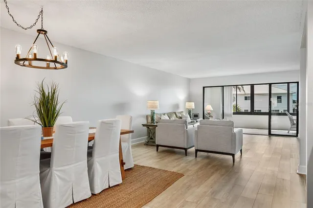 a dining room with wooden floor a chandelier a glass table and chairs