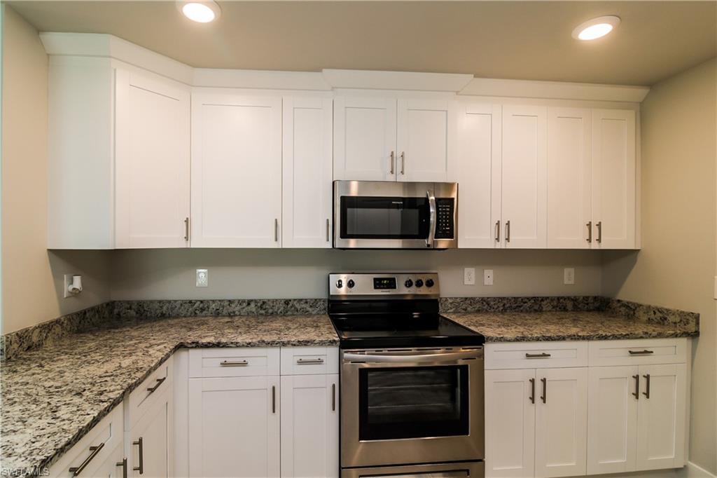 1004 Anson Avenue Lehigh Acres, FL 33971 - Photo 4 of 15 a kitchen with granite countertop white cabinets and black appliances